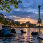 Un comerciante barre los cristales rotos del escaparate de su pequeña tienda en una calle de París tras una noche de disturbios