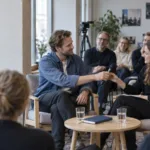 Toimistoympäristössä kädenpuristus symboloi yrityksen sisäisen yhteisön rakentamista ja avainhenkilön vaihdosta kasvuyrityksessä.