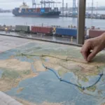 Una nave portacontainer cinese attraversa uno stretto mentre rotte alternative si diramano verso l’Africa e il Mediterraneo.
